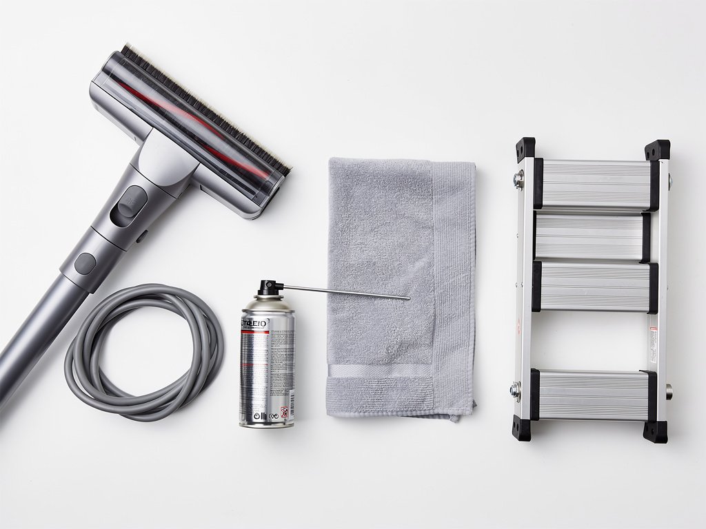 Supplies for cleaning a smoke detector: vacuum with brush attachment, compressed air, and microfiber cloth